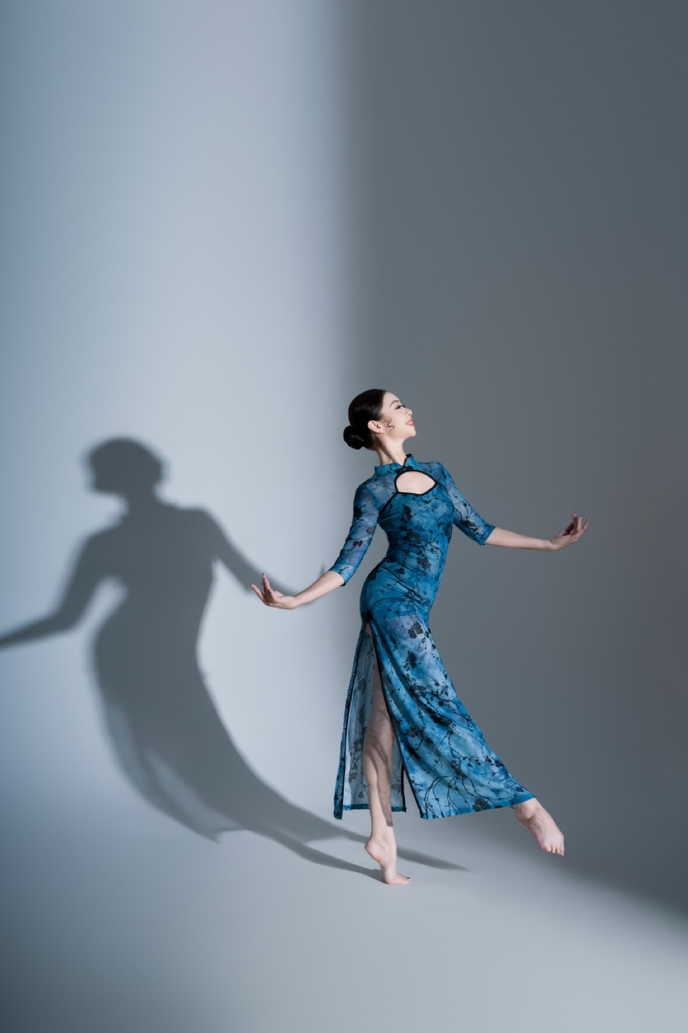 Grace Leung performing in a blue dress beside her shadow